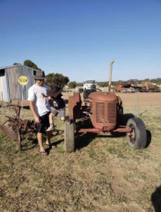 child jumping from tractor with man at Caravan Park and Farm Stay Roma looking at